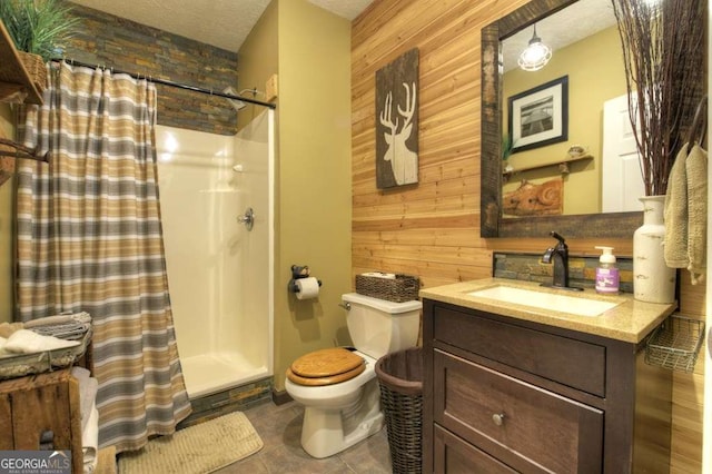 full bath featuring vanity, wooden walls, a shower stall, a textured ceiling, and toilet