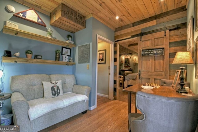 living area featuring wood finished floors, baseboards, wood ceiling, wood walls, and a barn door