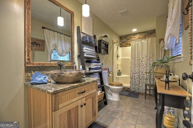 bathroom featuring vanity, tile patterned flooring, a textured ceiling, toilet, and shower / tub combo with curtain
