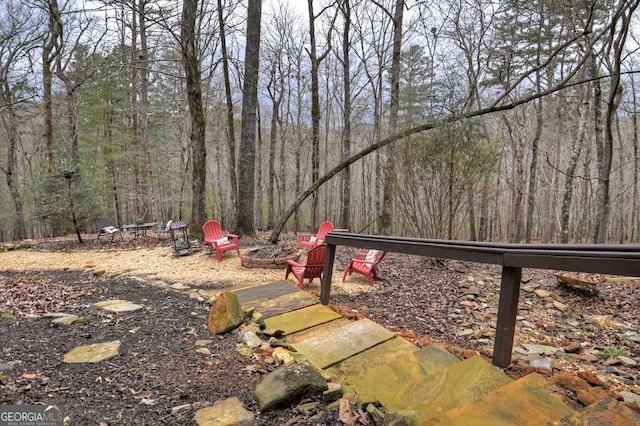 view of yard with a view of trees and an outdoor fire pit