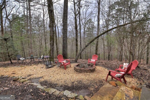 view of yard with a wooded view and an outdoor fire pit