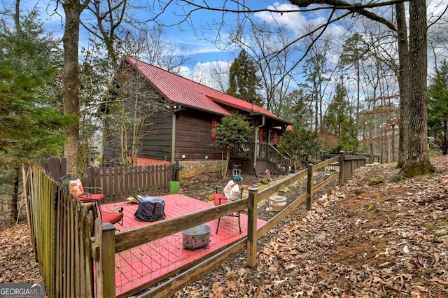 exterior space featuring a deck, fence, and metal roof