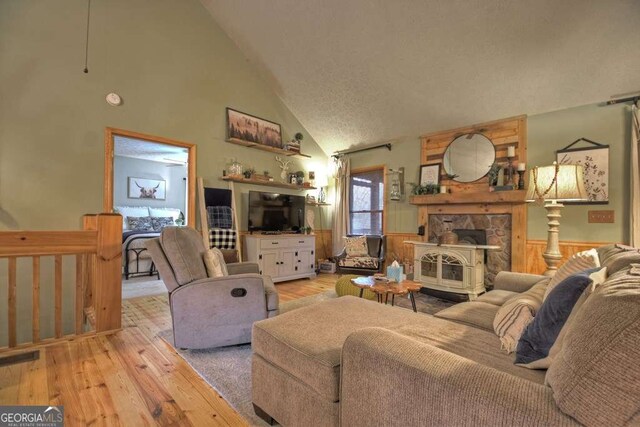 living room featuring a wainscoted wall, visible vents, high vaulted ceiling, and light wood-style floors