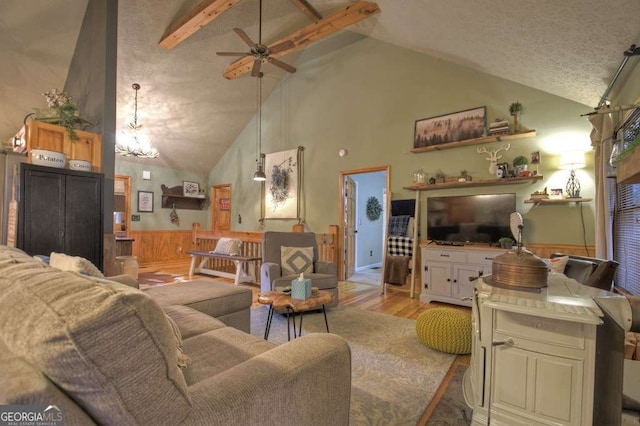 living room with light wood finished floors, ceiling fan, beamed ceiling, high vaulted ceiling, and a textured ceiling
