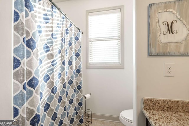 bathroom featuring toilet, a shower with shower curtain, and baseboards