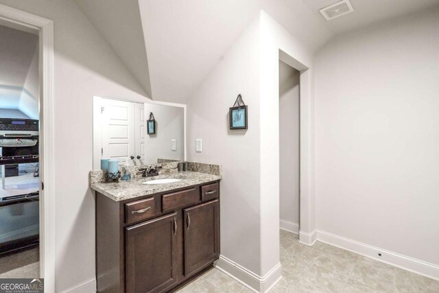 bathroom featuring vanity, lofted ceiling, baseboards, and visible vents
