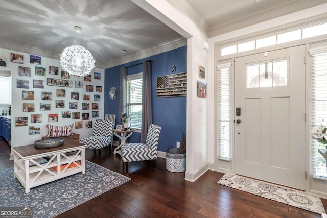 foyer entrance with a notable chandelier, wood-type flooring, baseboards, and ornamental molding