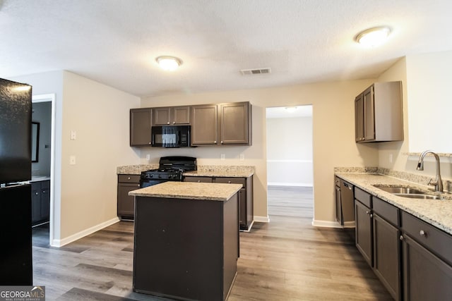 5345 Bridle Point Pkwy, Snellville, GA 30039 - kitchen with light stone counters, wood finished floors, black appliances, and a sink