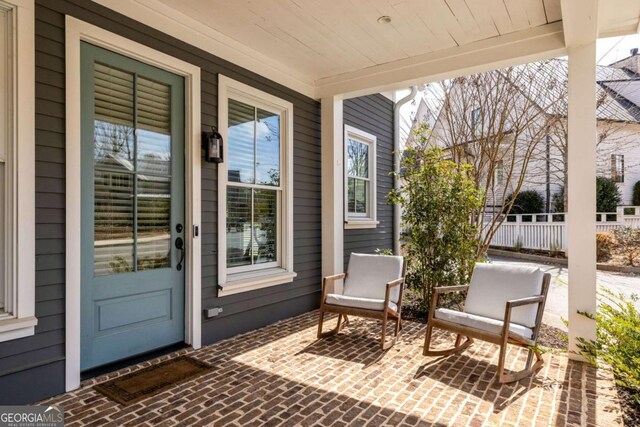 view of exterior entry with a porch and fence