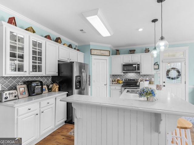 kitchen featuring a kitchen bar, white cabinetry, appliances with stainless steel finishes, light countertops, and glass insert cabinets