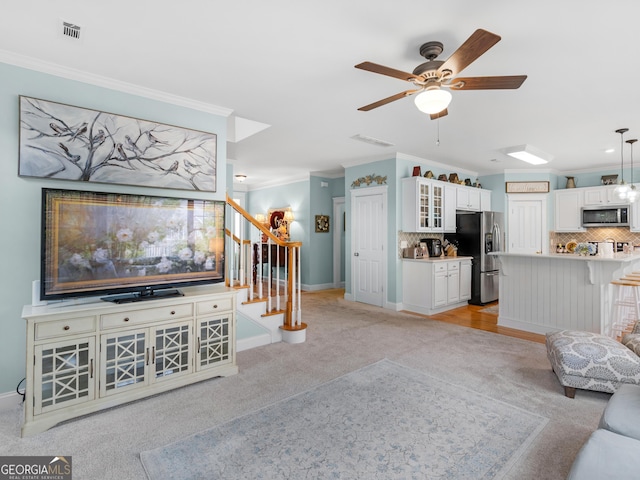 living area with baseboards, visible vents, ceiling fan, stairs, and ornamental molding