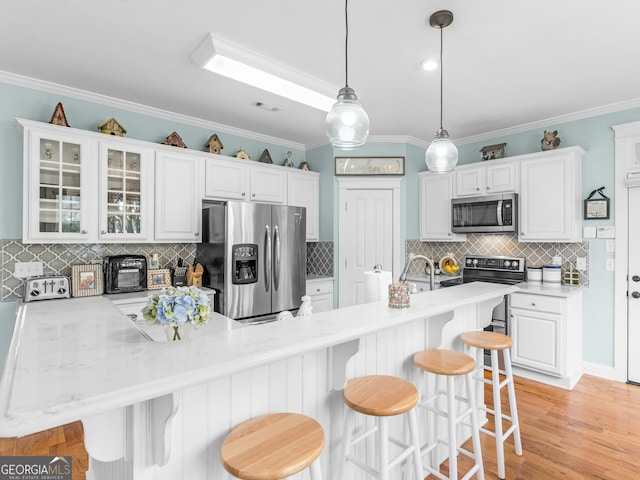 kitchen with a breakfast bar area, white cabinets, stainless steel appliances, and glass insert cabinets