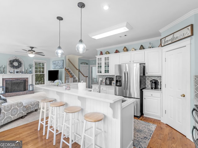 kitchen featuring glass insert cabinets, white cabinetry, a kitchen bar, and stainless steel fridge with ice dispenser