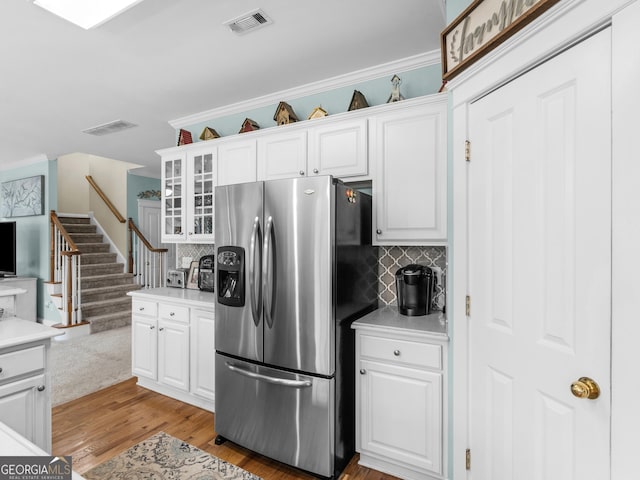 kitchen featuring visible vents, white cabinets, stainless steel fridge with ice dispenser, and ornamental molding