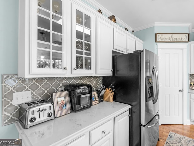 kitchen featuring glass insert cabinets, ornamental molding, stainless steel fridge with ice dispenser, and white cabinets