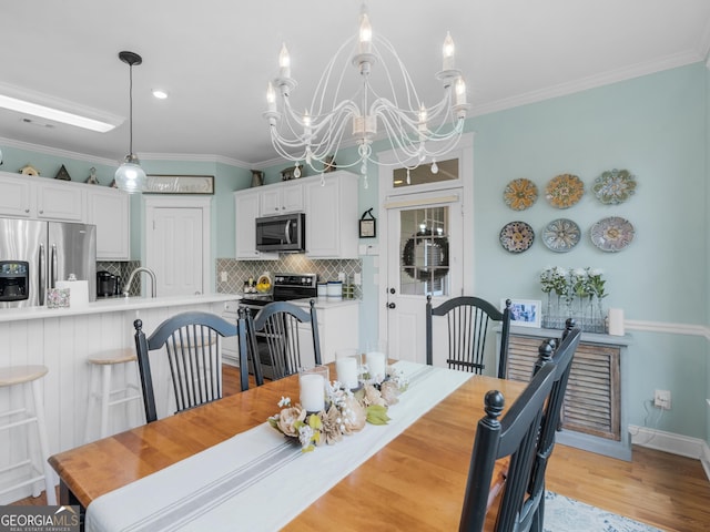 dining room with light wood-style flooring, ornamental molding, baseboards, and a chandelier