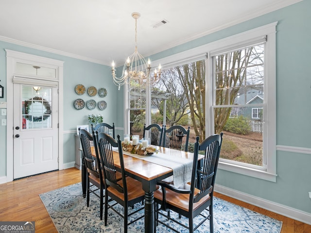 dining area featuring visible vents, a healthy amount of sunlight, light wood-type flooring, and an inviting chandelier