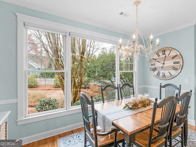 dining area featuring an inviting chandelier, plenty of natural light, wood finished floors, and ornamental molding