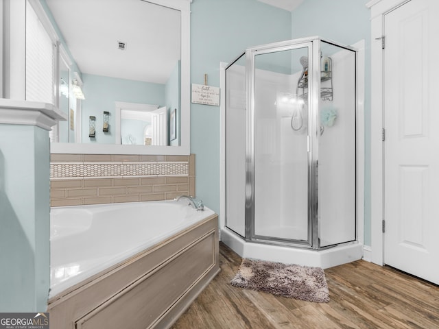 bathroom featuring a garden tub, wood finished floors, a stall shower, and visible vents