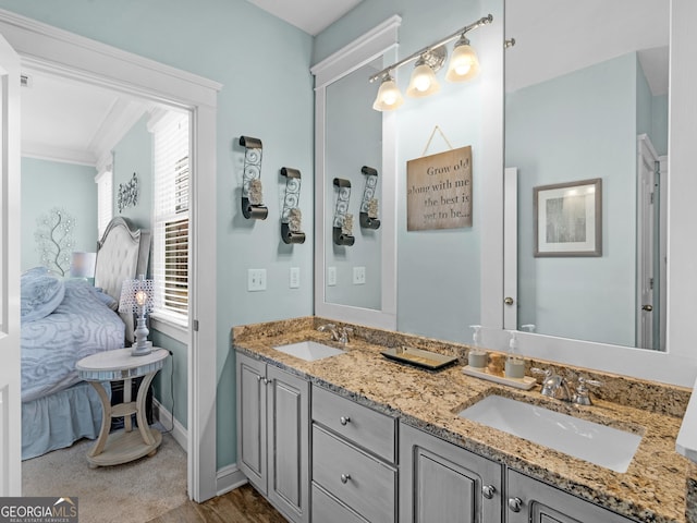 bathroom with a sink, baseboards, ornamental molding, and double vanity