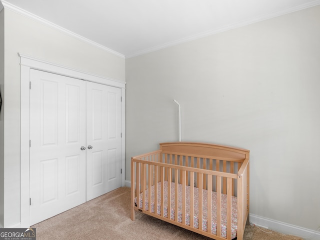 bedroom featuring baseboards, carpet floors, a crib, a closet, and crown molding