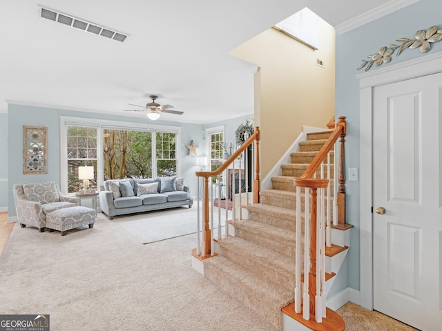 living area featuring ceiling fan, visible vents, ornamental molding, and stairs