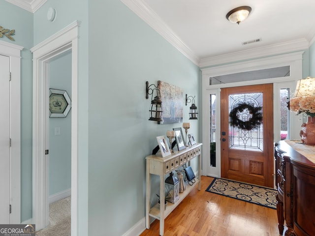 entrance foyer with visible vents, wood finished floors, baseboards, and ornamental molding