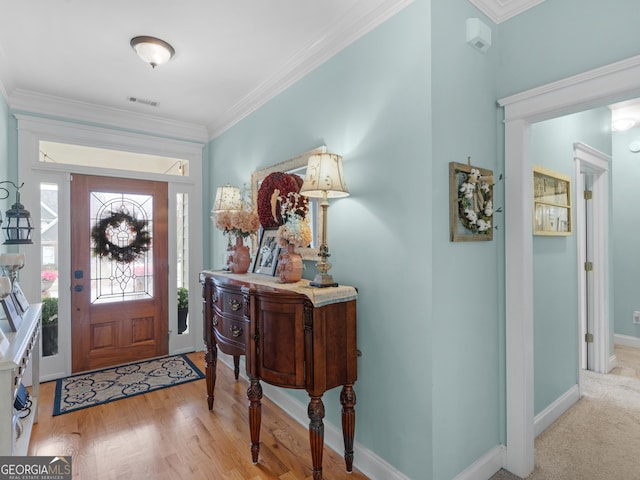 foyer with wood finished floors, visible vents, baseboards, and ornamental molding