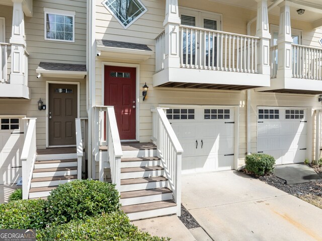 entrance to property featuring a garage, driveway, and a shingled roof