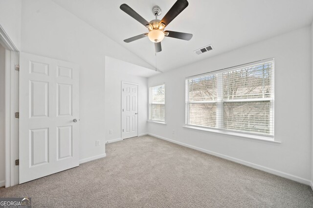 unfurnished bedroom with a ceiling fan, carpet, visible vents, baseboards, and lofted ceiling