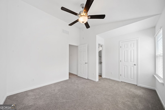 unfurnished bedroom featuring baseboards, visible vents, lofted ceiling, ceiling fan, and carpet flooring