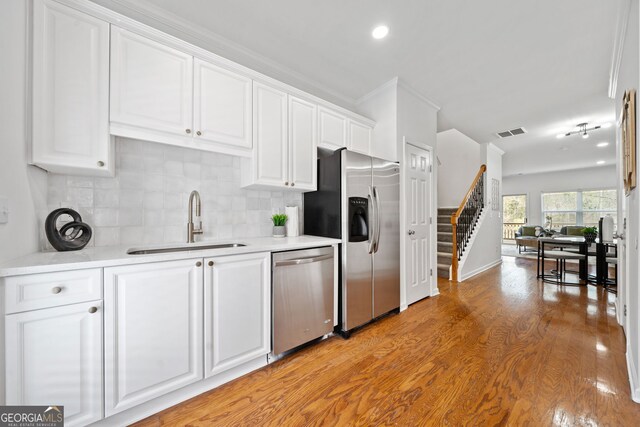kitchen featuring visible vents, a sink, decorative backsplash, appliances with stainless steel finishes, and white cabinetry