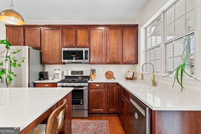 3810 Branch Bluff Ln, Cumming, GA 30040 - kitchen with pendant lighting, wood finished floors, brown cabinetry, stainless steel appliances, and a sink
