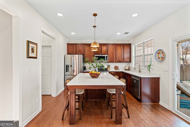 3810 Branch Bluff Ln, Cumming, GA 30040 - kitchen with wood finished floors, stainless steel appliances, light countertops, a kitchen breakfast bar, and a center island