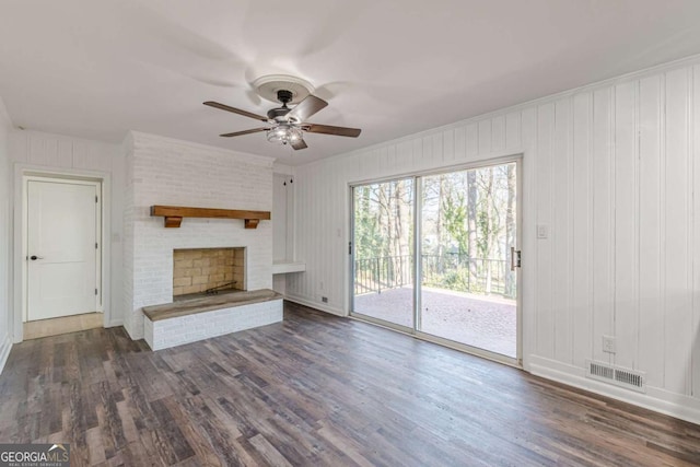 unfurnished living room with a ceiling fan, visible vents, baseboards, dark wood finished floors, and a brick fireplace
