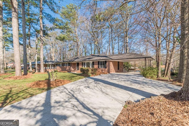 ranch-style home with brick siding, an attached carport, concrete driveway, and a front yard