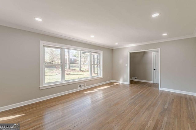 spare room with recessed lighting, crown molding, baseboards, and wood finished floors