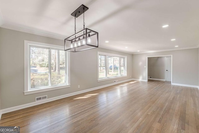 unfurnished dining area with visible vents, baseboards, wood finished floors, and ornamental molding