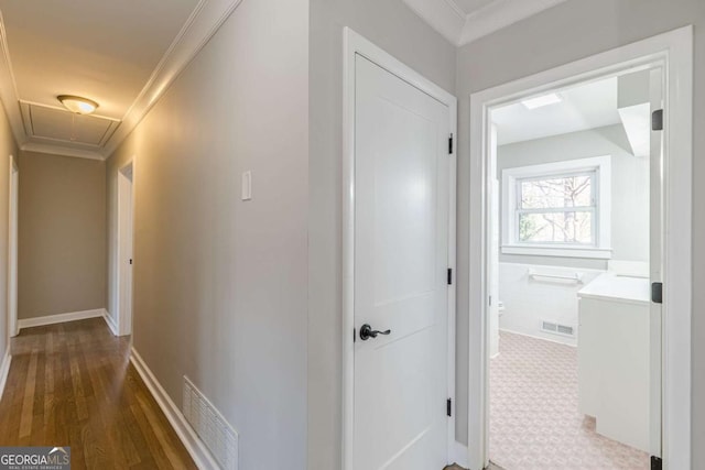 hallway with visible vents, attic access, and crown molding