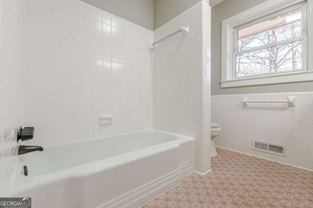 bathroom with visible vents, a wainscoted wall, shower / washtub combination, toilet, and tile walls