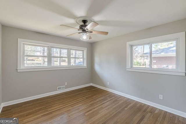 unfurnished room with wood finished floors, baseboards, visible vents, and ceiling fan