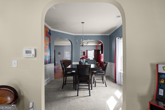 dining space with a wainscoted wall, carpet flooring, arched walkways, and ornamental molding