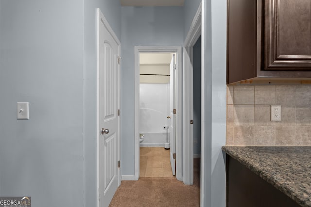 hallway with baseboards and light colored carpet
