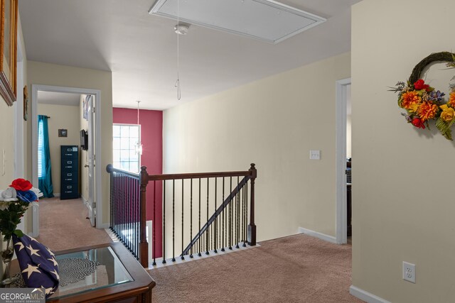 hallway with attic access, carpet flooring, and an upstairs landing