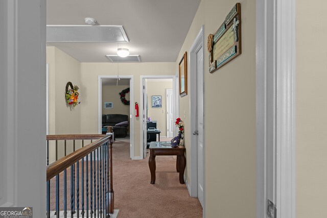 corridor with attic access, an upstairs landing, visible vents, and carpet floors