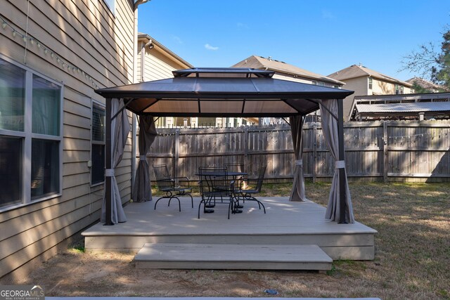 wooden terrace with a gazebo, outdoor dining space, and fence