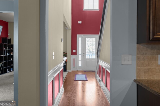 foyer entrance with light wood-style flooring, wainscoting, and a decorative wall