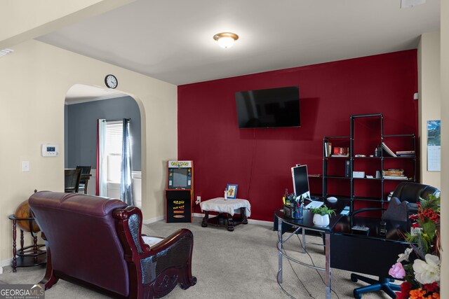 living area featuring carpet, arched walkways, and baseboards