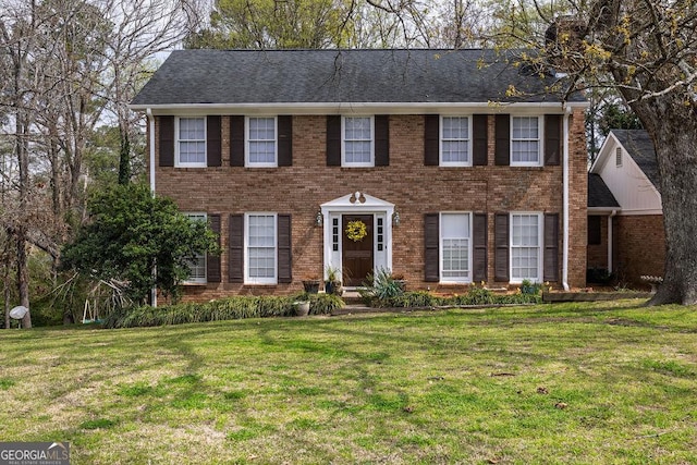 colonial inspired home with brick siding and a front yard