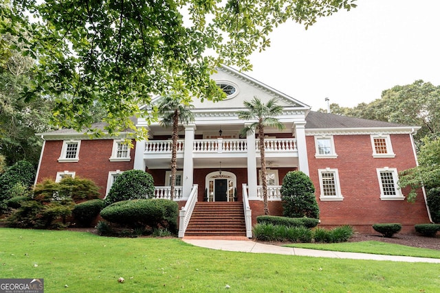 neoclassical home featuring brick siding, a front lawn, stairway, a porch, and a balcony